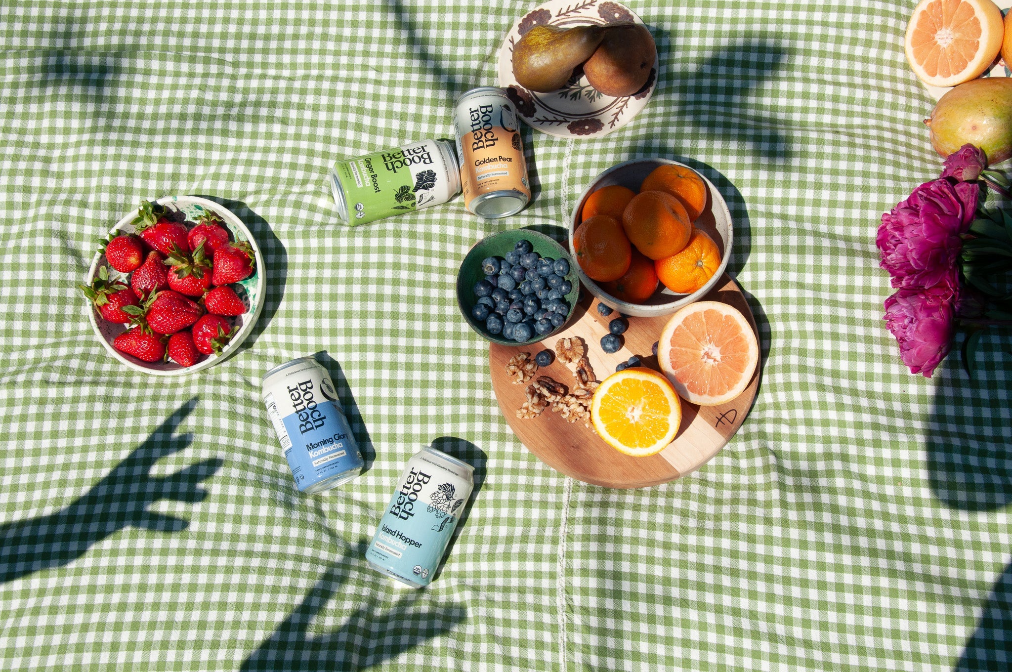 two guys sitting on a rock on the beach, drinking Better Booch kombucha